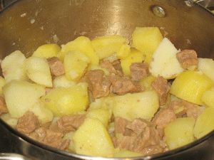 перемешать тушёную картошку с мясом